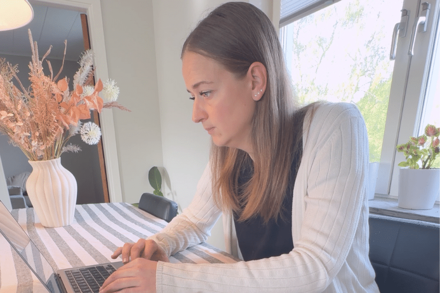 Sophie arbetar vid laptop vid köksbord, analyserar e-postmarknadsföring och rensar inaktiva kontakter i e-postlista.