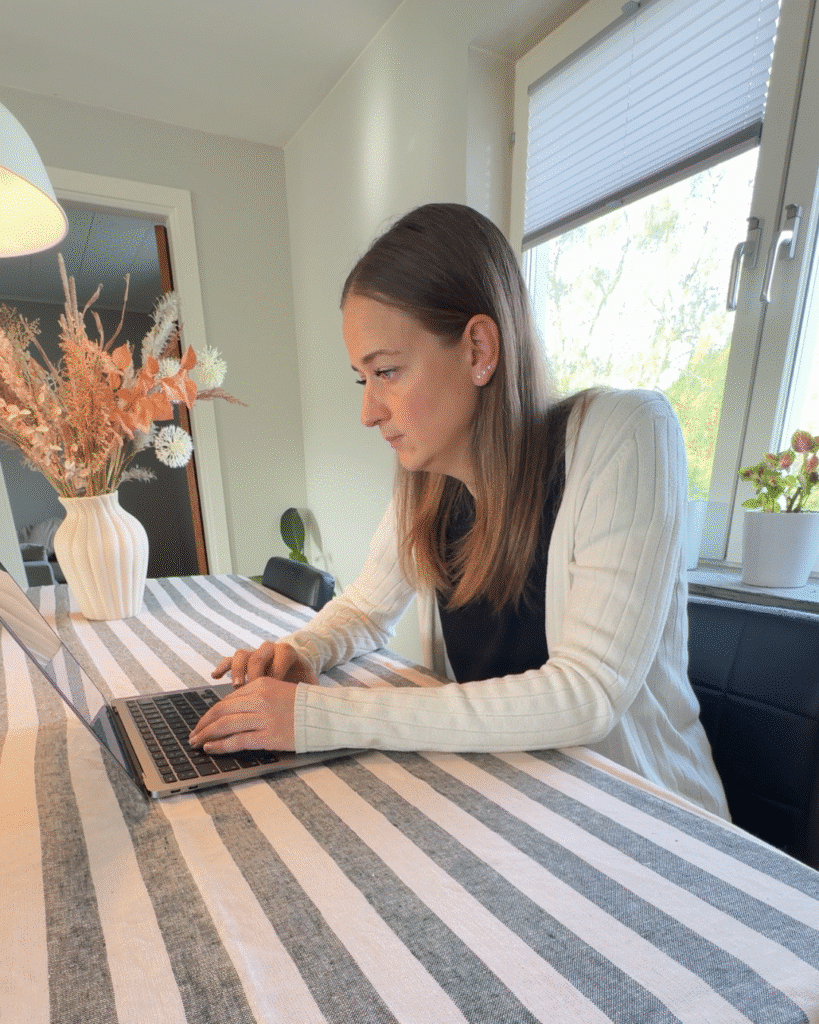 Kvinna arbetar fokuserat vid en laptop med att bygga hemsida.